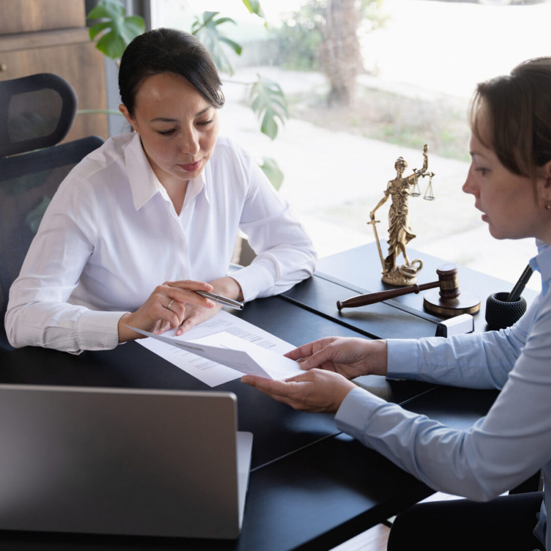 Two women discussing documents in office.