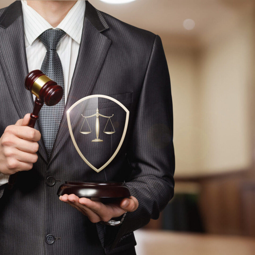 A professional in a suit holds a gavel and a shield with scales of justice. The backdrop features a courtroom, emphasizing the importance of law and justice during proceedings.