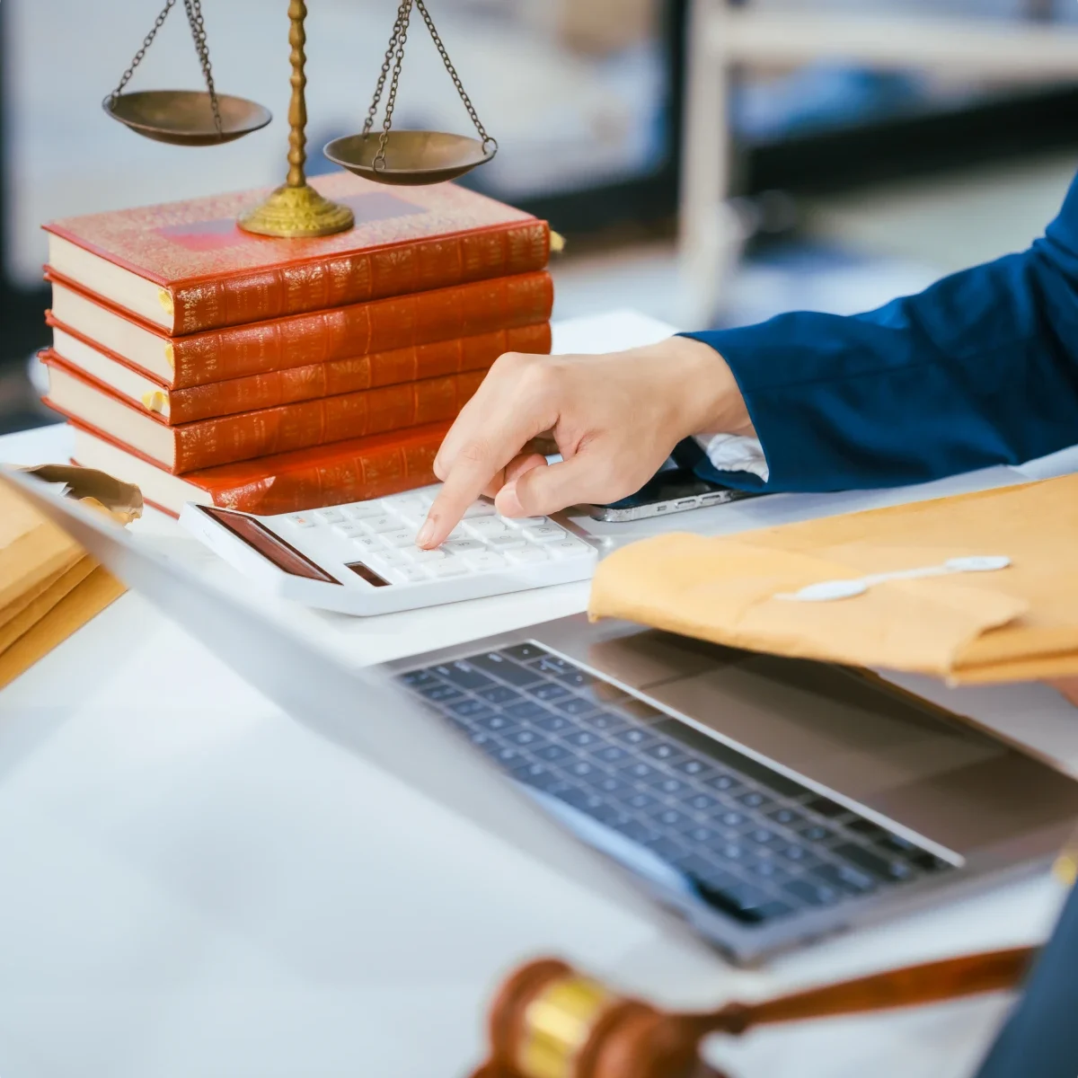 Person using calculator near legal books, gavel.